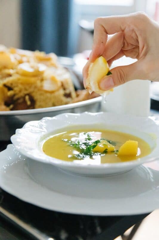 A Person Squeezing Lemon on a Soup